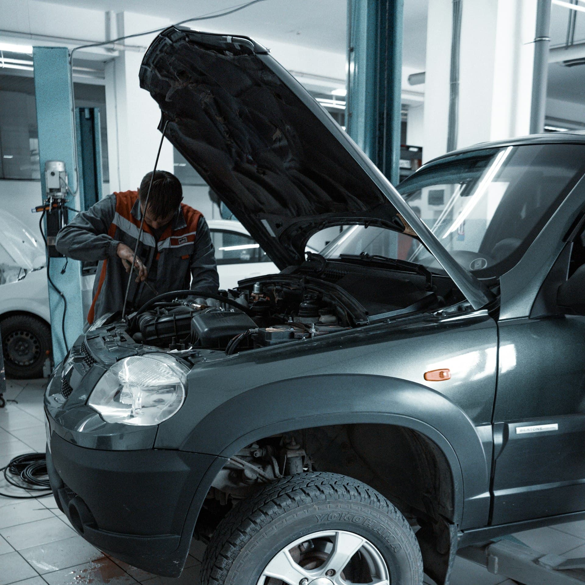 Mechanic inspecting a vehicle's engine in a garage